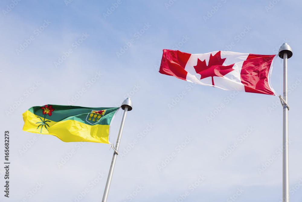 Saskatchewan and Canada flags against blue sky