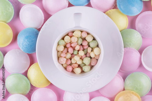 Small pastel color sweeties in a white cup.