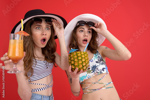 Shocked two women drinking cocktails.