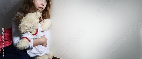 Frightened girl hugs a teddy bear