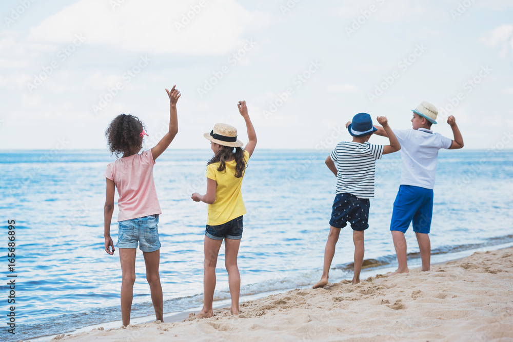 back view of group of kids throwing stones at seaside together back view of group of kids throwing stones at seaside together