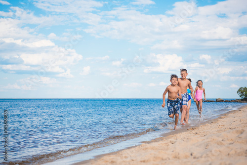 multiethnic group of little children running on sandy beach