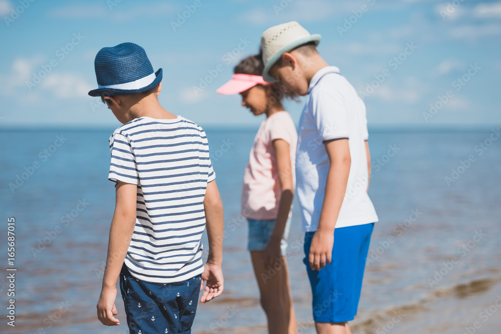 selective focus of multicultural little children standing at seaside selective focus of multicultural little children standing at seaside