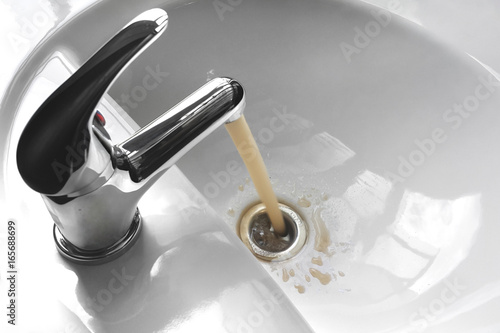 Water Tap With Running Dirty Muddy Water in a Sink