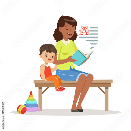 Teacher reading a book to little boy while sitting on a bench, kids education and upbringing in preschool or kindergarten, colorful characters