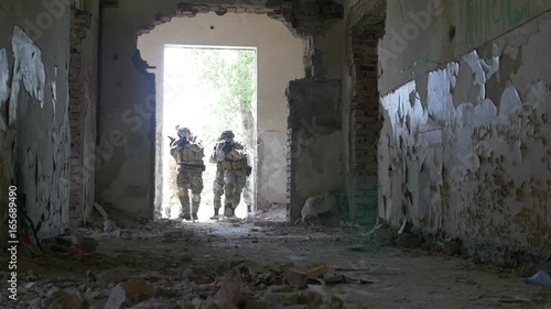 Slow motion of special infiltration unit walking to an entrance of an abandoned building searching enemy photo