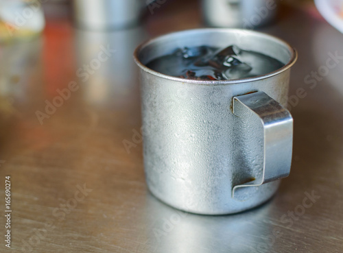 Metal glass or cup of cold water with ice on stainless steel table background