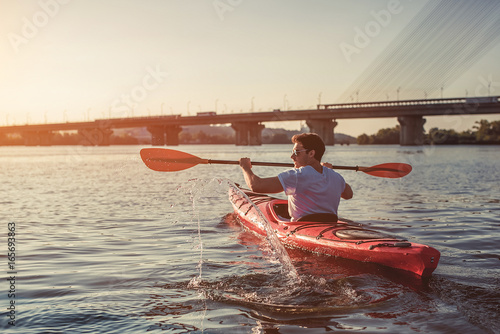 Man kayaking on sunset