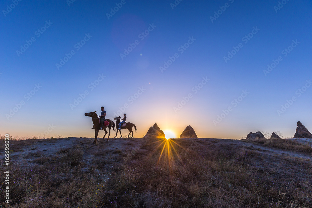 Man and horse silhouette on the background of valley at Cappadocia,Anatolia,Turkey.The great tourist attraction of Cappadocia best places to fly with hot air balloons.Rocks looking like mushrooms.