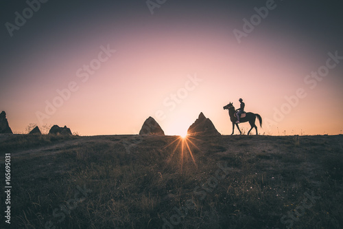 Man and horse silhouette on the background of valley at Cappadocia,Anatolia,Turkey.The great tourist attraction of Cappadocia best places to fly with hot air balloons.Rocks looking like mushrooms.