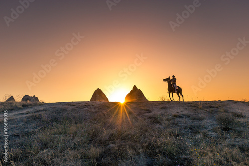 Man and horse silhouette on the background of valley at Cappadocia Anatolia Turkey.The great tourist attraction of Cappadocia best places to fly with hot air balloons.Rocks looking like mushrooms.