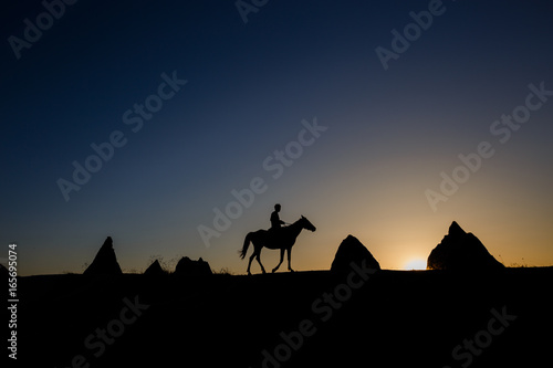 Man and horse silhouette on the background of valley at Cappadocia Anatolia Turkey.The great tourist attraction of Cappadocia best places to fly with hot air balloons.Rocks looking like mushrooms.