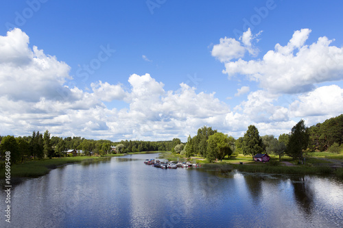 Beautiful scenery in the countryside next to a river in Finland. Sunny summer day with some clouds in the sky. Traditional village view.