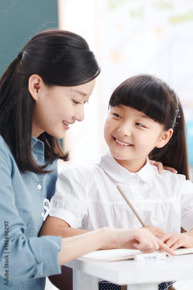 Female teacher helping student studying in classroom Female teacher helping student studying in classroom