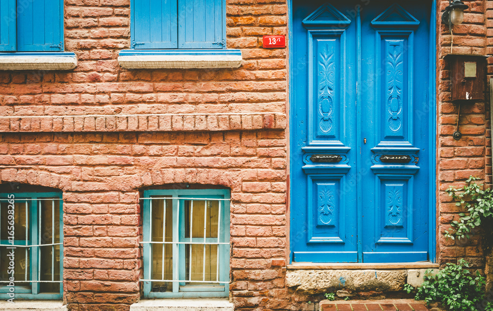 ISTANBUL,TURKEY - May 6,2017:Facade view of vintage style old red brick wall house with blue door and turquoise window. Vintage building and old aged design in Balat,Istanbul,Turkey.