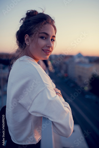 young girl on the roof is smiling and looking at the camera