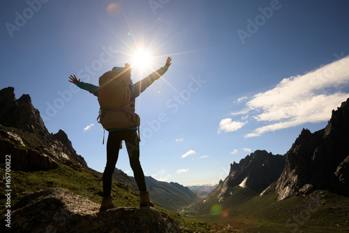 cheering woman with backpack hiking in mountains travel lifestyle success concep