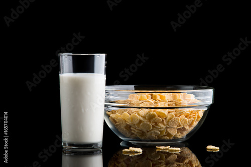 Glass of milk and cornflakes on a black background photo