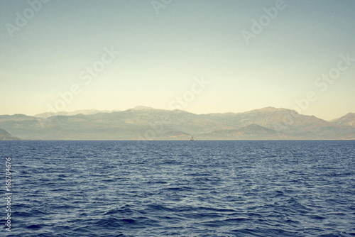 sea, mountains landscape, sailboat sailing far from seashore