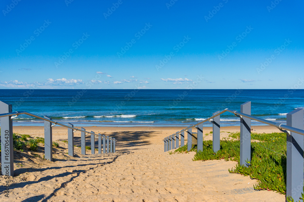 Seascape of beach entrance with wooden rails and sand shore Seascape of beach entrance with wooden rails and sand shore