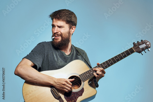 Man with a beard on a blue background holds a guitar, music, musical instruments