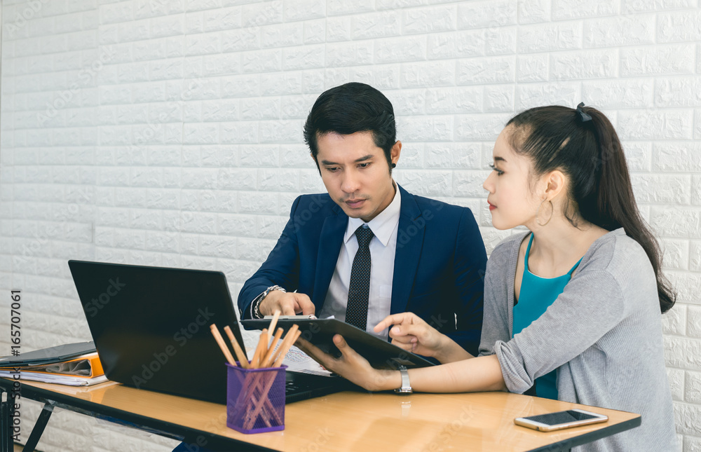 Asian Business People Working in Office , Describe the Project , Analyze Plans with Workmate on the Desk Asian Business People Working in Office , Describe the Project , Analyze Plans with Workmate on the Desk