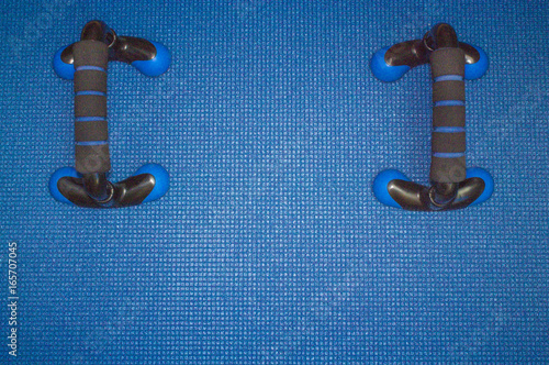 Blue background. Mat for sport, yoga and meditation. Two push-up bars. photo