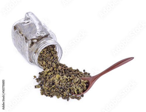 Tea leaves in a glass jug and on a wooden spoon isolated from a white background.