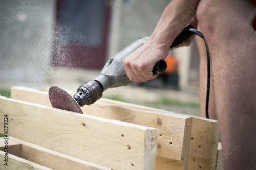 Obraz na plátně Young man hands grinding / sanding wood by automatic grinder, sawdust, woodwork,