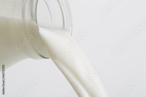 Pouring Milk from a glass bottle. Closeup image.