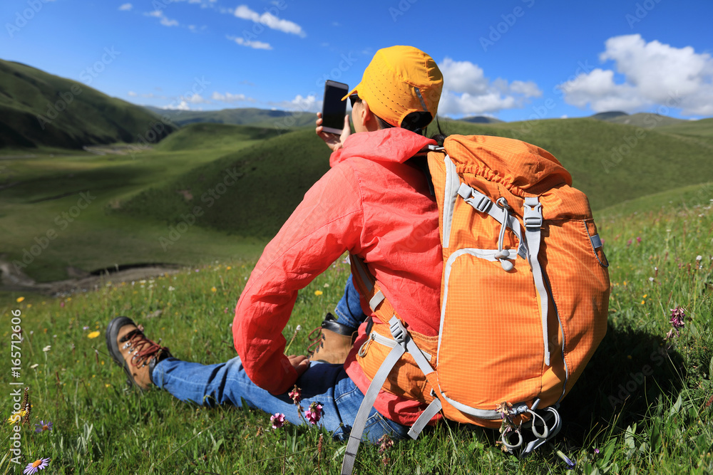 young woman taking photo with smartphone hiking in prairie mountains young woman taking photo with smartphone hiking in prairie mountains