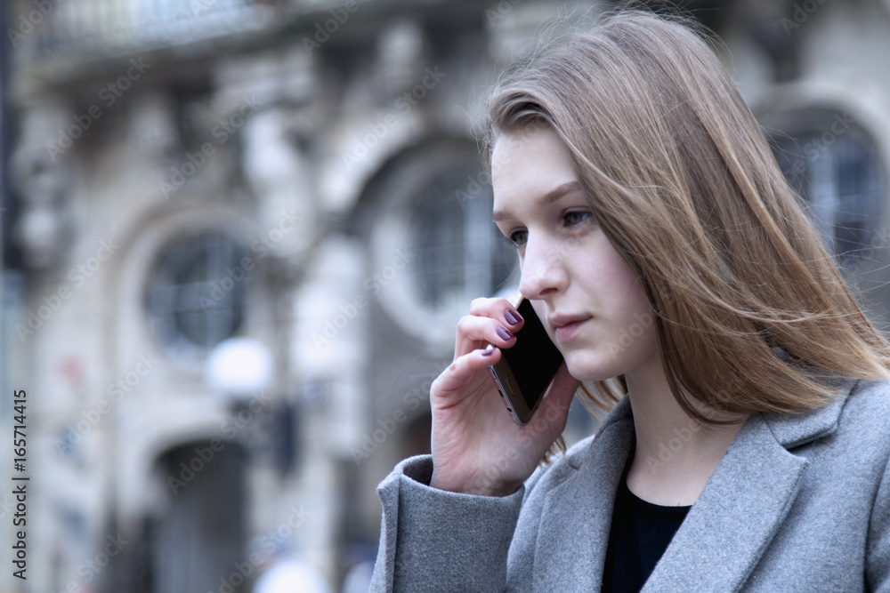 Portrait of young serious business woman with smartphone outdoors as symbol of singlessness of purpose, freelance, success and wealth Portrait of young serious business woman with smartphone outdoors as symbol of singlessness of purpose, freelance, success and wealth