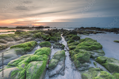 Colorful sunset with natural coastal rocks. Image contain soft focus due to long exposure.