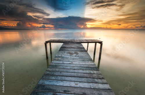 Fototapeta Naklejka Na Ścianę i Meble -  View of beautiful sunset with wooden jetty. image contain soft focus due to long expose.