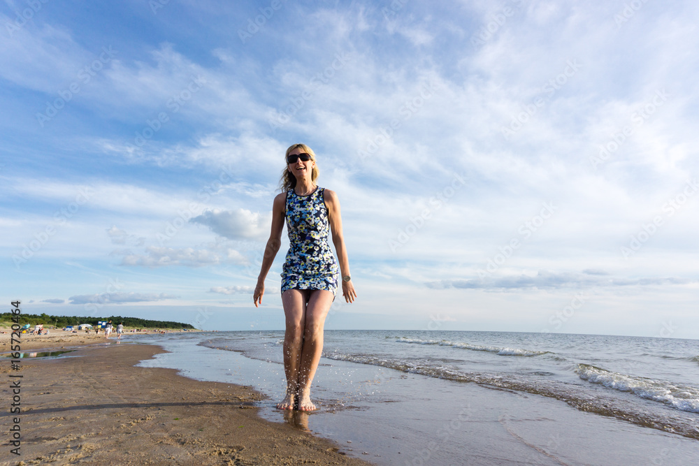 Happy young woman in short dress jumping on the beach