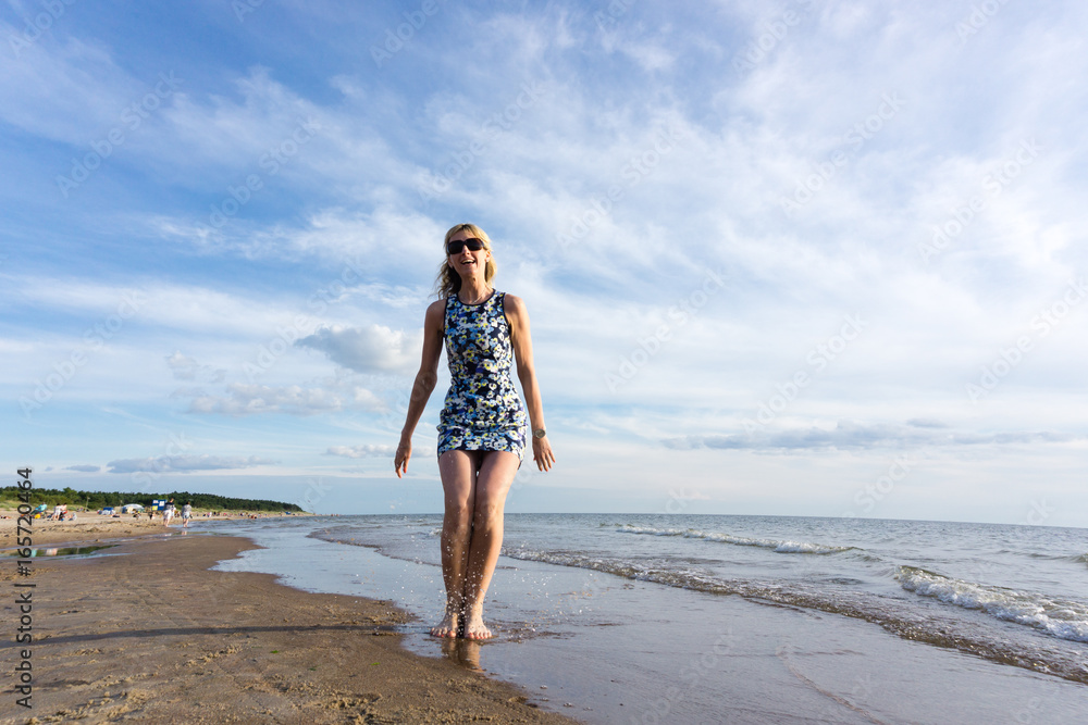 Happy young woman in short dress jumping on the beach Happy young woman in short dress jumping on the beach