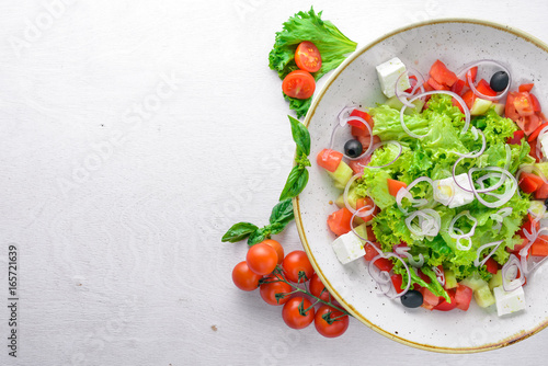Greek salad of fresh vegetables and cheese. On a wooden background. Top view. Free space for your text.