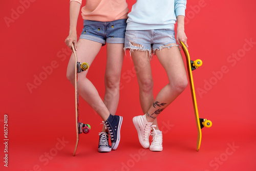 Cropped image of young two ladies holding skateboards.