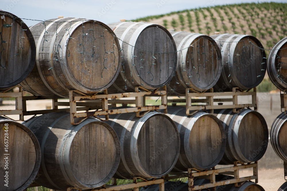 Wine barrels at vineyard with grape vines in background Wine barrels at vineyard with grape vines in background