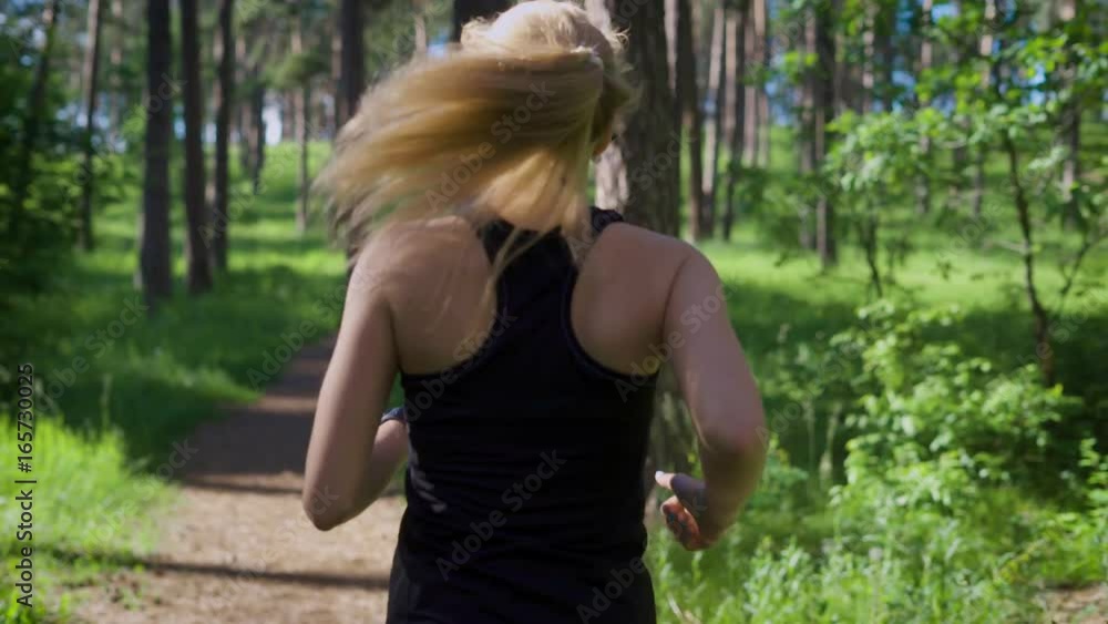 Woman jogging in the park. She switching music on her music player Woman jogging in the park. She switching music on her music player