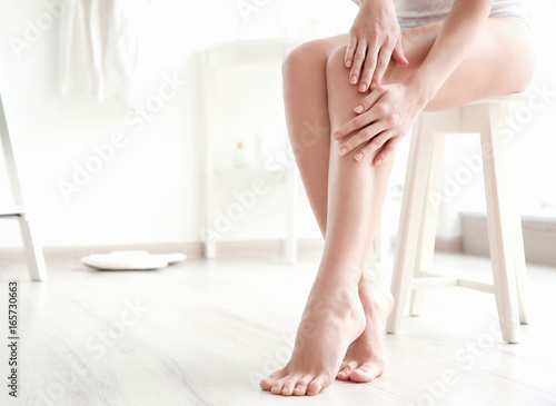 Woman touching smooth skin on leg at home. Epilation concept