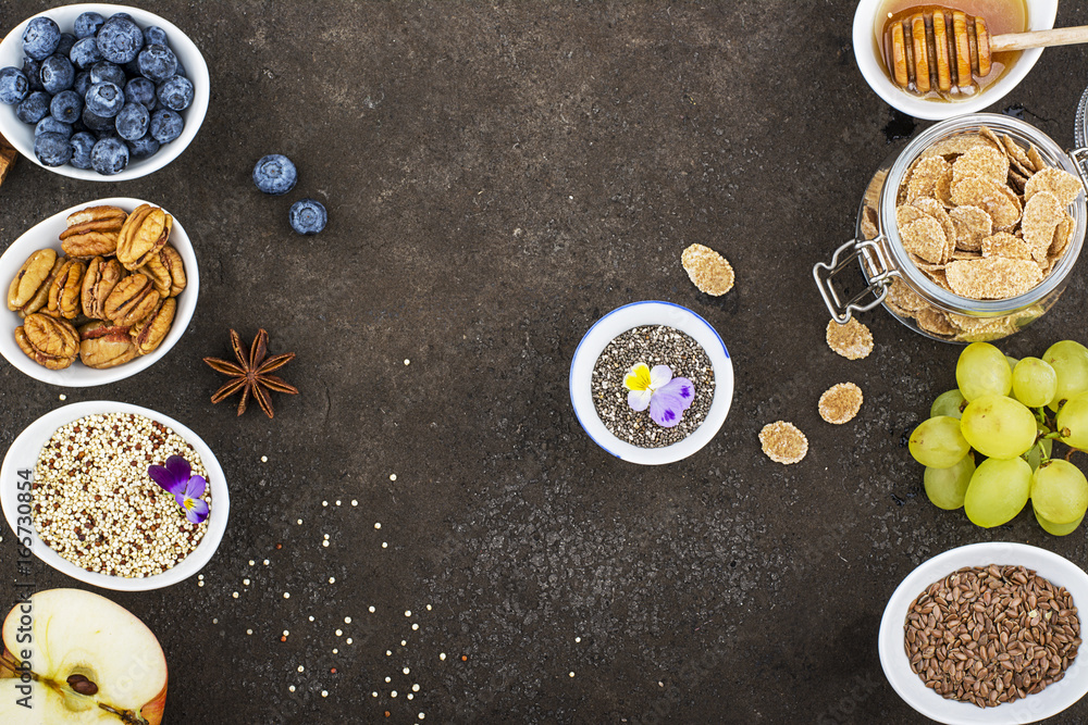 Ingredients for a healthy seasonal autumn breakfast: apples, grapes, pecan, chia seeds, quinoa, flax seeds, honey, flakes, oatmeal, blueberries, edible flowers on the background. Top View Ingredients for a healthy seasonal autumn breakfast: apples, grapes, pecan, chia seeds, quinoa, flax seeds, honey, flakes, oatmeal, blueberries, edible flowers on the background. Top View