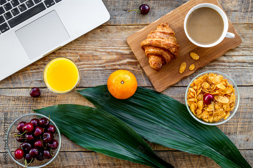 French breakfast. Fresh croissant, coffee, muesli, oranges, cherry on wooden table background top view