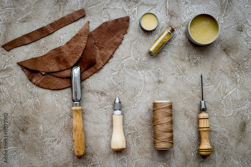 Leather craft. Tanner's tools on grey stone background top view