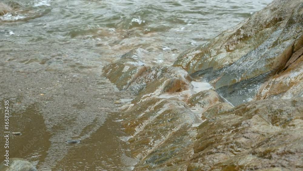 Slowly panning across rocks with waves falling onto the beach Slowly panning across rocks with waves falling onto the beach