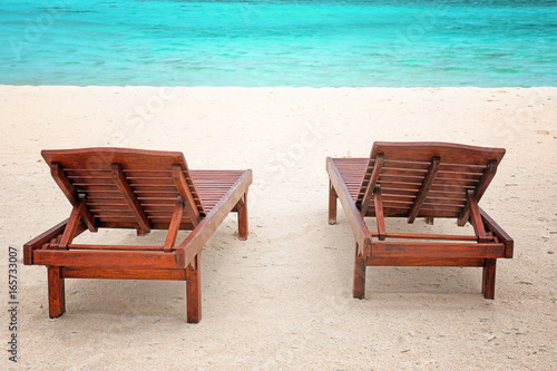 Wooden sun loungers on sea beach in summer day © Africa Studio