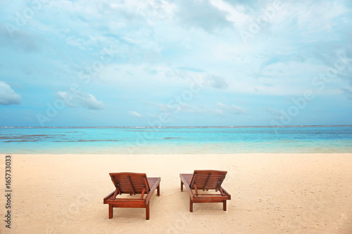 Wooden sun loungers on sea beach in summer day © Africa Studio