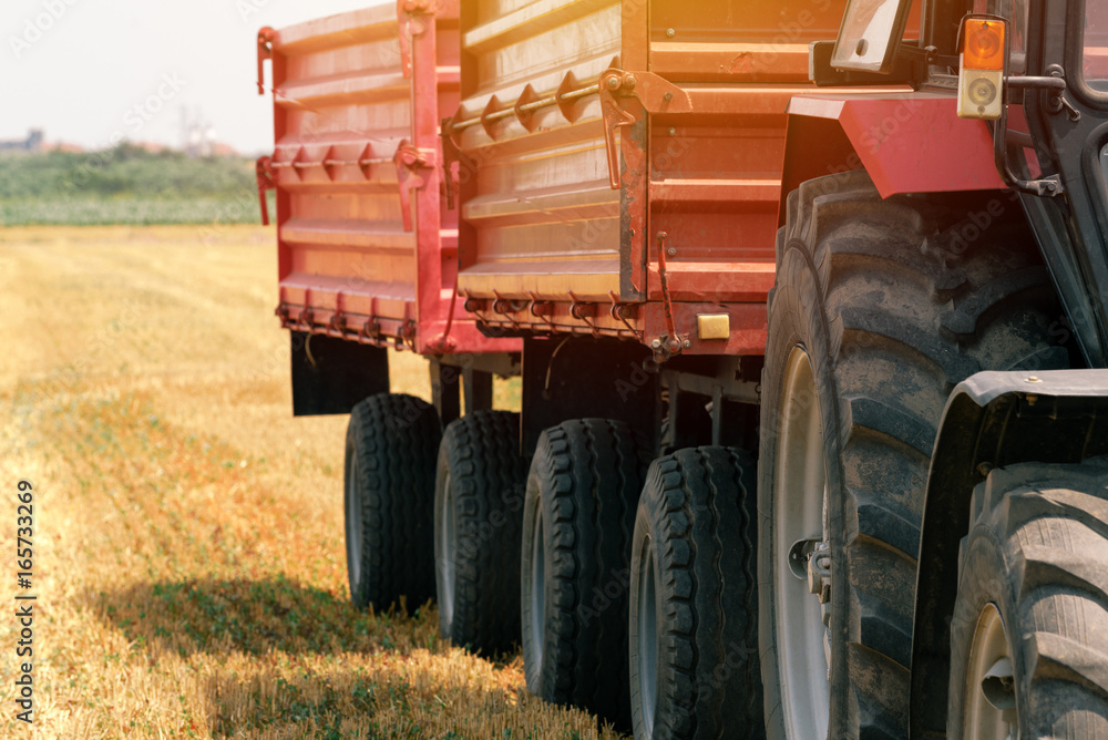 Naklejka premium Tractor with wagon trailer in field