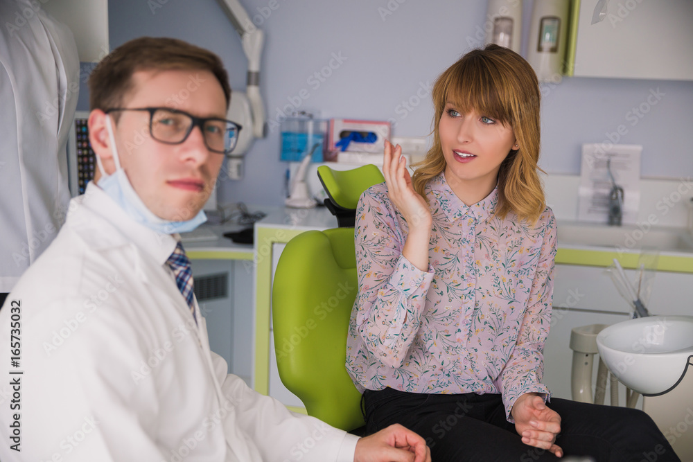 Male dentist  talking with female patient