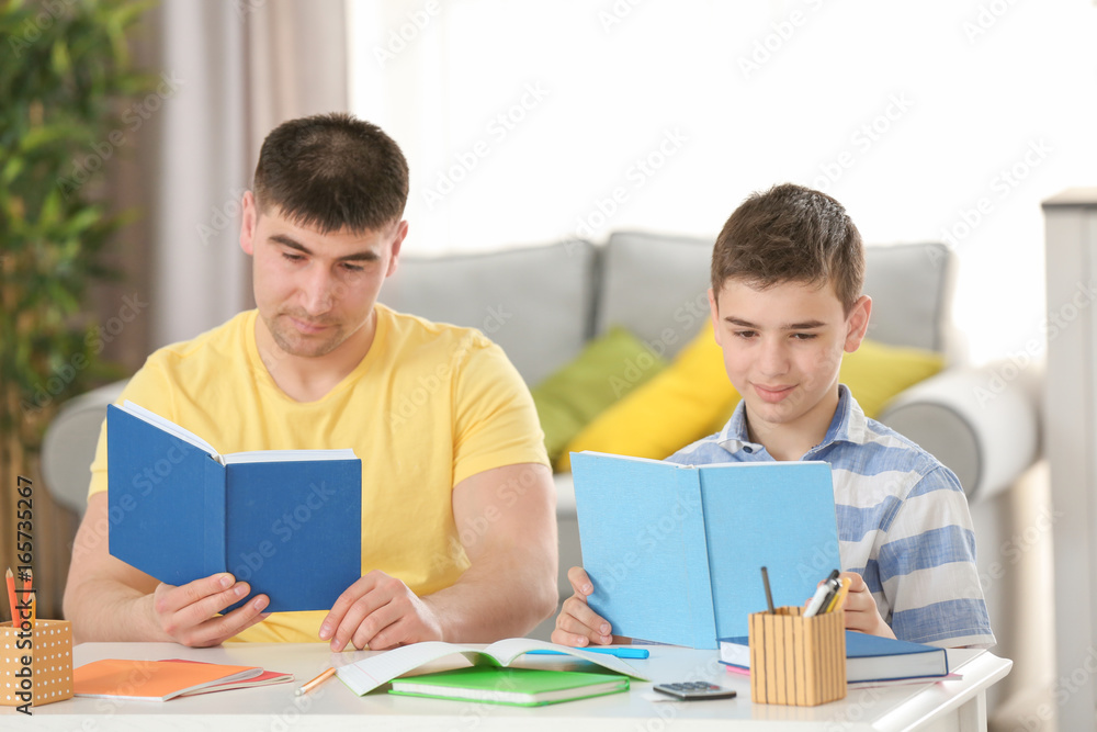 Father and son doing homework together indoors Father and son doing homework together indoors